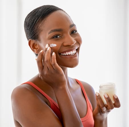 Happy black mature woman applying cream on face Facials in New York, NY